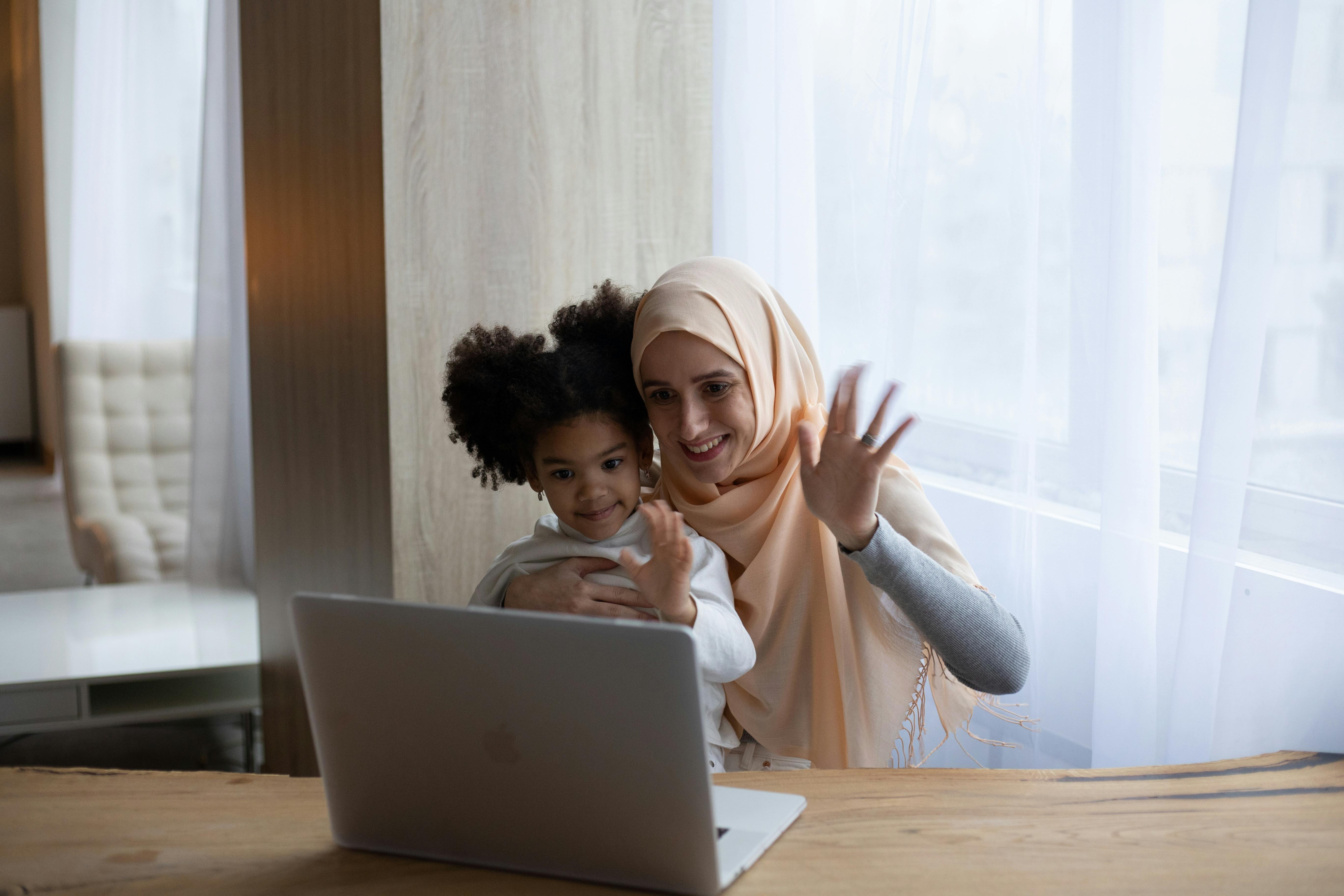 Mother and child waving at laptop